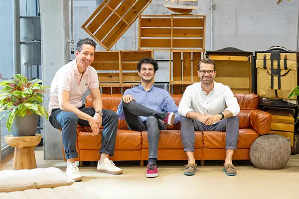 Three men smiling sitting on a sofa together